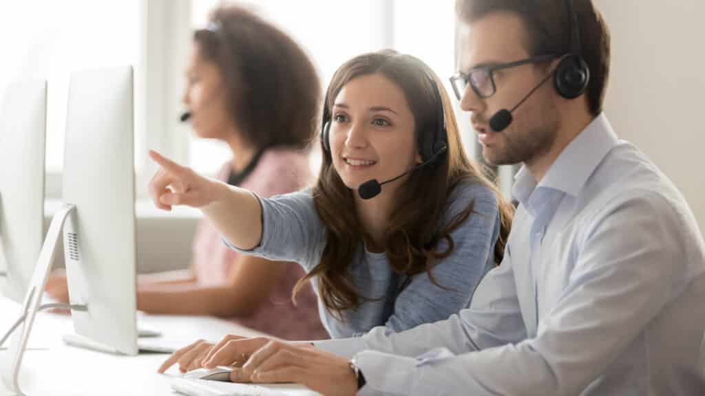 Call center agent operator telemarketer helping colleague