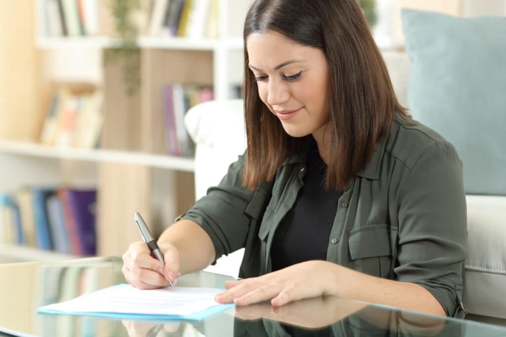 Satisfied woman signing contract sitting at home
